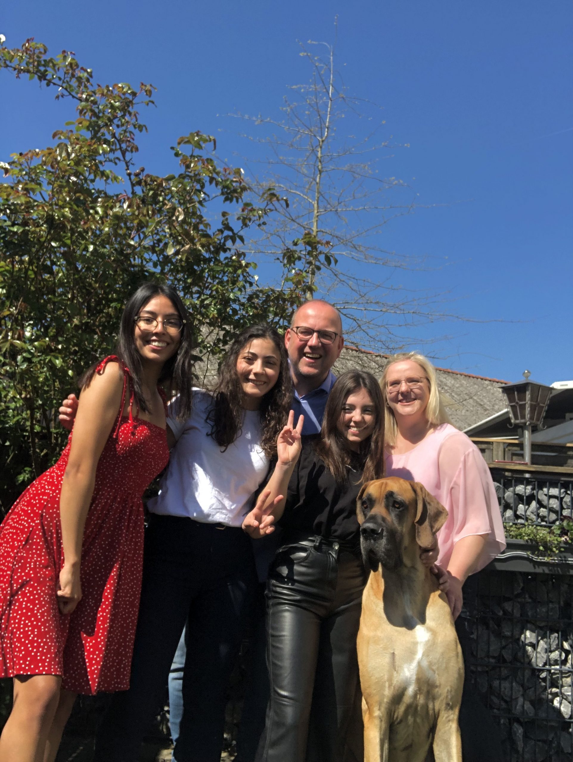 Gruppenfoto mit Gastfamilie und Hund vor ihrem Haus