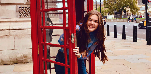Austauschschülerin in einer roten Telefonzelle in London