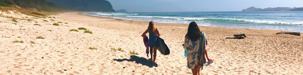 Austauschschülerinnen mit Surfbrettern am Strand in Neuseeland