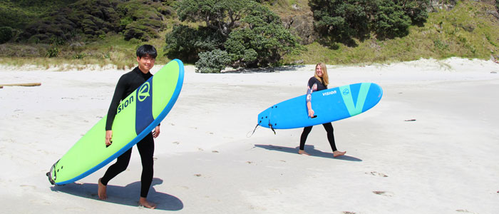 Zwei Austauschschüler mit Surfboards am Strand