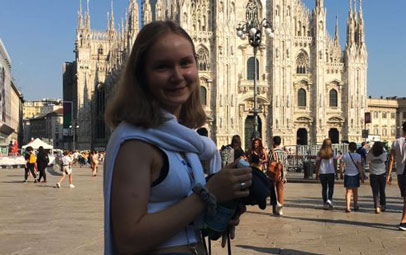 Austauschschülerin mit Kamera vor einer Kathedrale in Italien