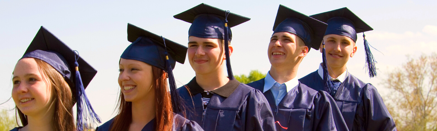 Glückliche High School Schüler und Schülerinnen in Absolventenkleidern und Hüten auf ihrer Absolventenfeier