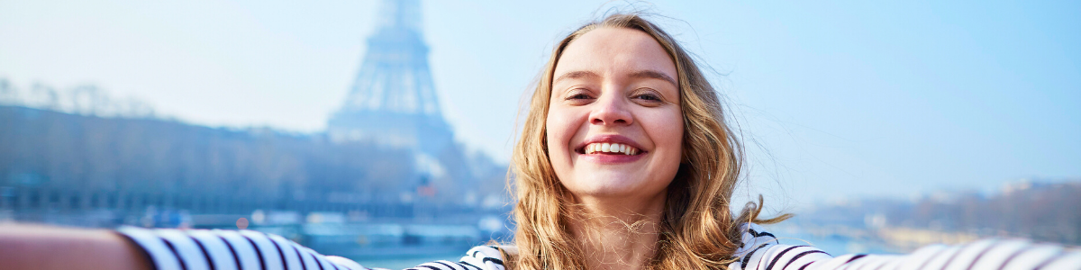 Glückliche Austauschschülerin macht ein Selfie vor dem Eifelturm in Paris