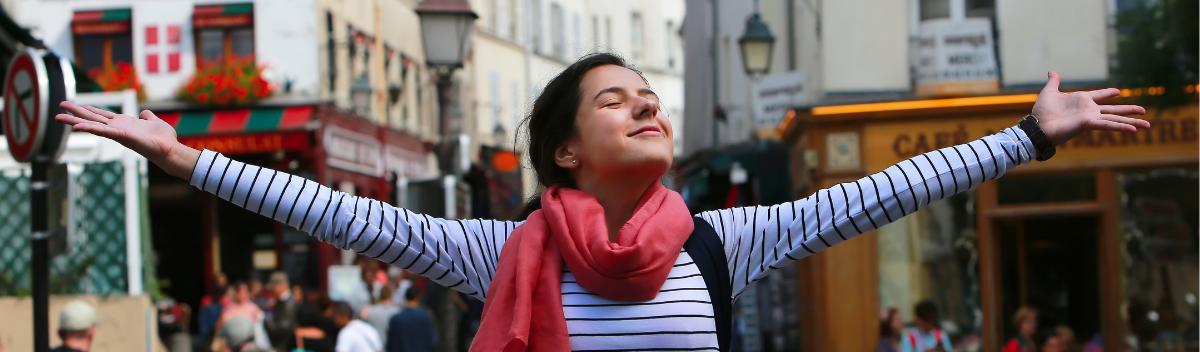 Austauschschülerin breitet ihre Arme aus in einer französischen Stadt