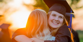 High School Schülerinnen umarmen sich bei ihrer Absolventenfeier