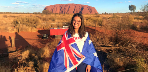 Austauschschülern mit Australien Flagge vor dem Uluru in der Wüste von Australien