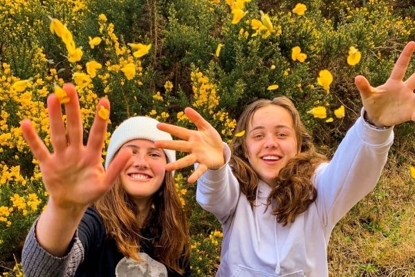 Zwei Austauschschülerinnen vor einem gelben Blumenbeet in Irland
