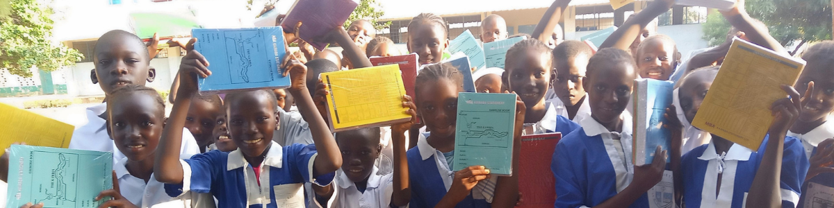 Schüler und Schülerinnen in Gambia mit Schulbüchern vor der Schule