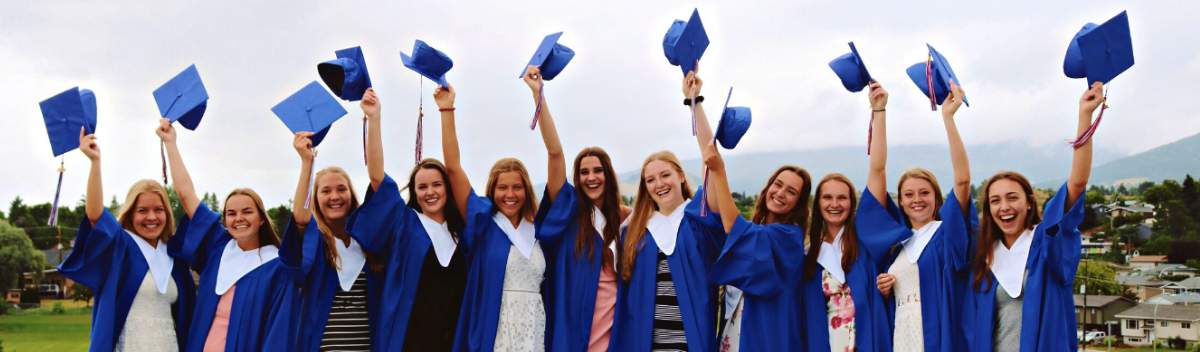 Gruppenfoto mit High School Absolventinnen, die ihre blauen Hüte in die Luft werfen