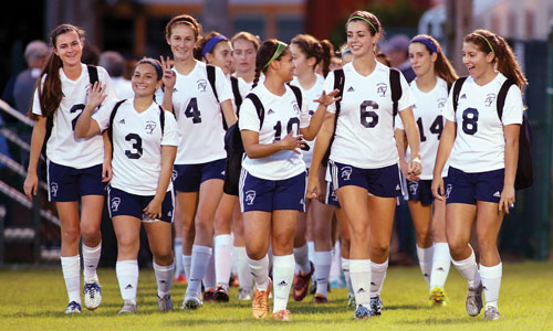 Frauenfußballmannschaft laufen auf den Sportplatz an einer High School in den USA
