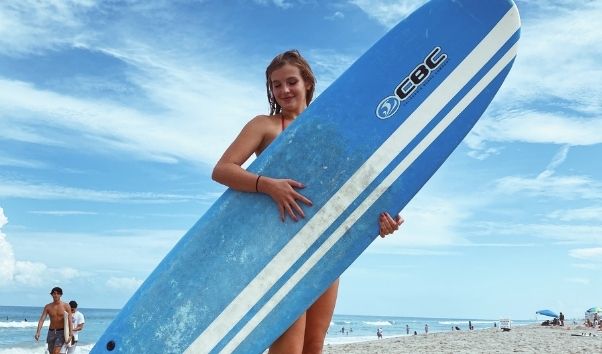 Mädchen mit Surfbrett am Strand