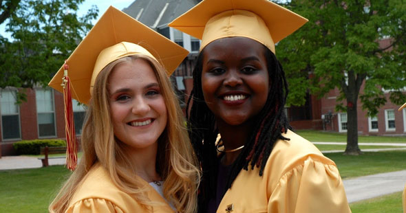 Zwei Schülerinnen in gelben Umhängen bei der Abschlussfeier ihrer High School in den USA