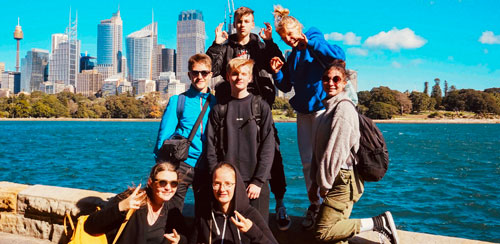 Austauschschüler und Schülerinnen am Meer vor einer Skyline