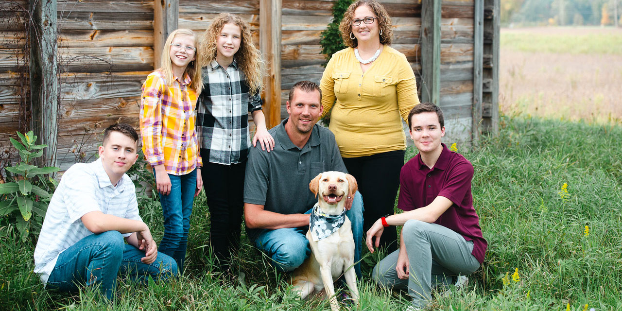 Austauschschüler mit seiner Gastfamilie und Hund auf einem Bauernhof