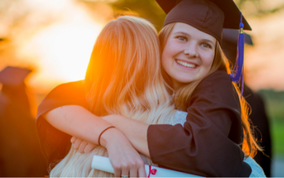 High School Absolventin mit Diploma in der Hand umarmt ihre Freundin bei Sonnenuntergang