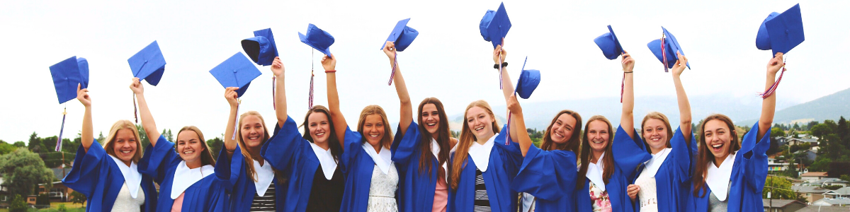 Gruppe von High School Schülerinnen tragen blaue Absolventenkleidung und werfen ihre Hüte in die Luft
