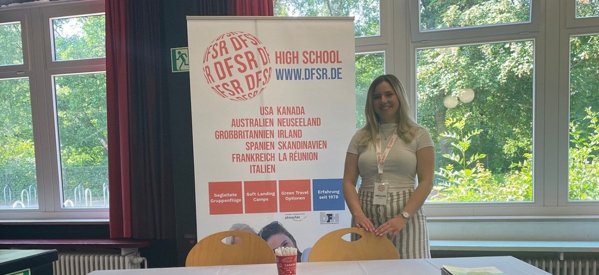 Freie Mitarbeiterin auf einer Jugendbildungsmesse zum Thema High School Aufenthalte vor dem DFSR Messestand.