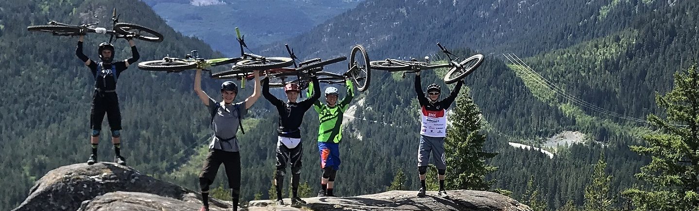 Austauschschüler halten ihre Fahrräder in die Luft in den Bergen